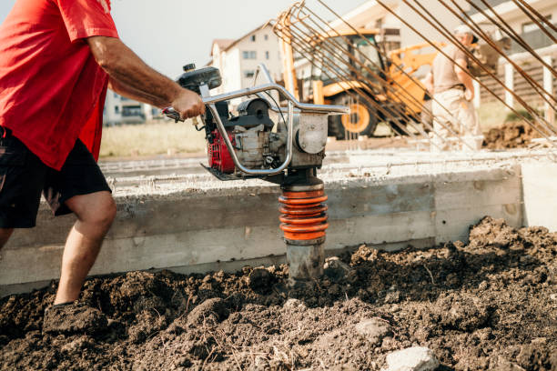 industrial construction worker compacting soil with vibration compaction machine - tamper imagens e fotografias de stock