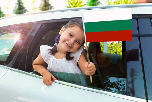 Girl holding Bulgarian Flag in the car.