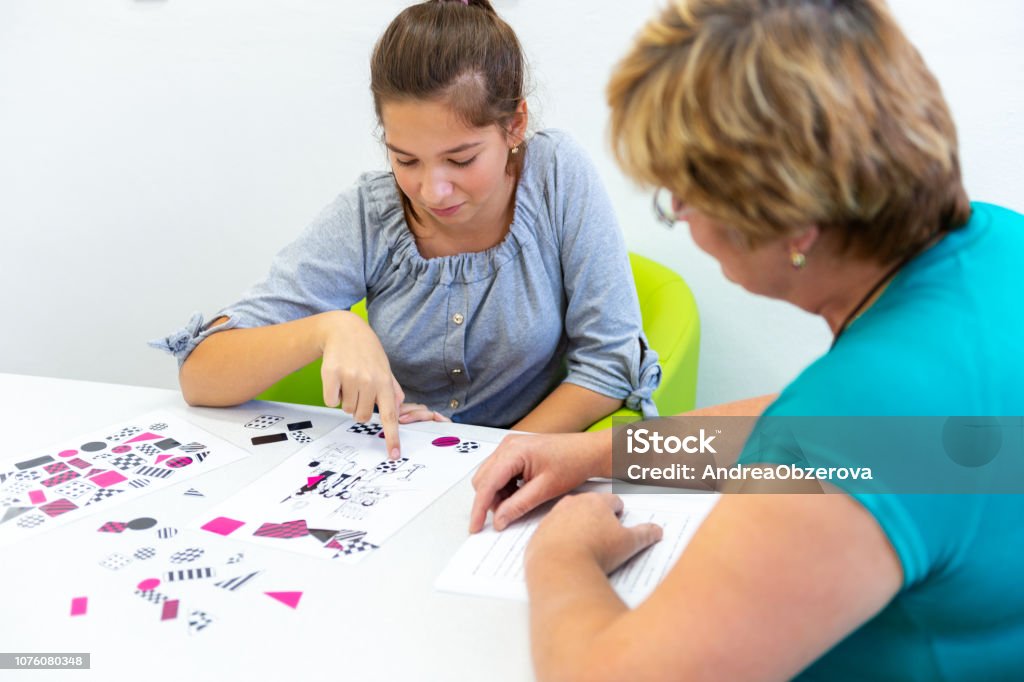 Therapist working with a teenage girl with learning difficulties to master logical tests. Learning Difficulty Stock Photo