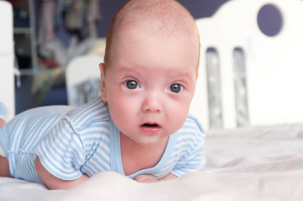 istock Cute baby is lying on the bed and learning to hold his head. 1076090200