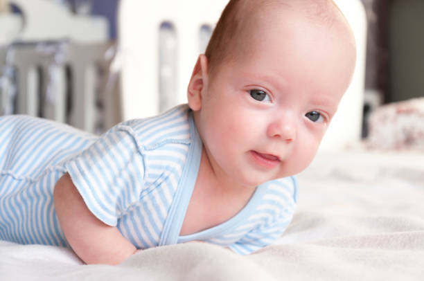 istock Cute baby is lying on the bed and learning to hold his head. 1076090210