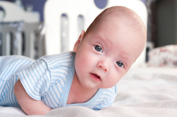 istock Cute baby is lying on the bed and learning to hold his head. 1076090230