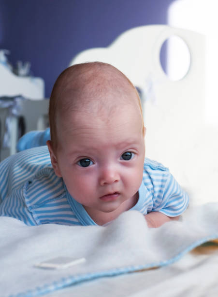istock Cute baby is lying on the bed and learning to hold his head. 1076090280