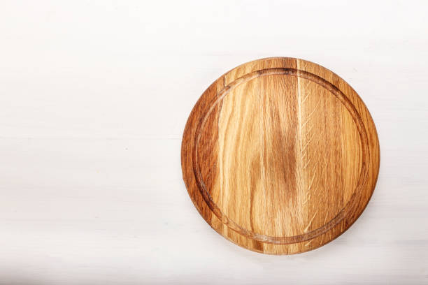 empty round pizza board on white wooden background.