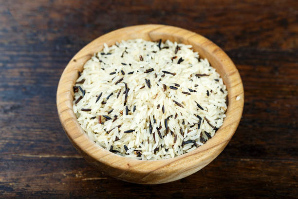 riz sauvage noir et blanc dans une plaque de bois sur un fond en bois. - rice black wild rice dry photos et images de collection