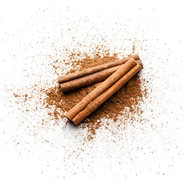 Cinnamon powder heap isolated on white background Top view of cinnamon powder heap with two cinnamon sticks isolated on white background. Predominant colors are brown and white. High key DSRL studio photo taken with Canon EOS 5D Mk II and Canon EF 100mm f/2.8L Macro IS USM. cinnamon photos stock pictures, royalty-free photos & images