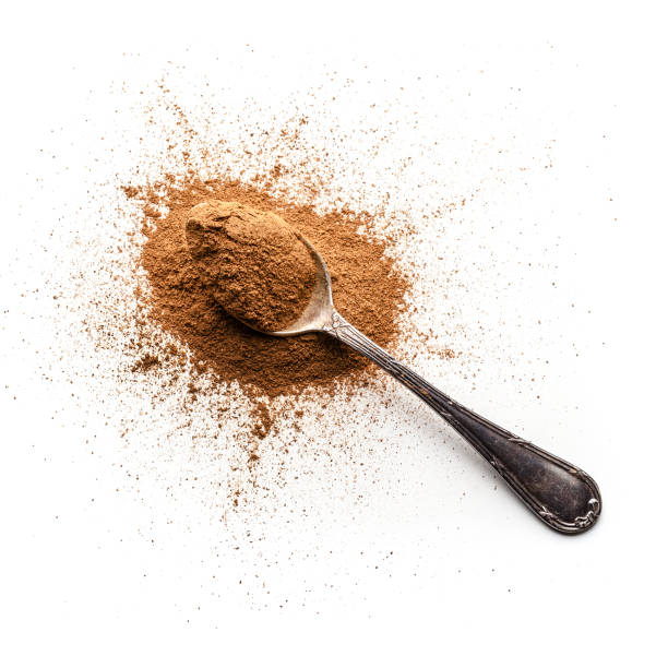 Top view of cinnamon powder heap with a metal spoon isolated on white background. Predominant colors are brown and white. High key DSRL studio photo taken with Canon EOS 5D Mk II and Canon EF 100mm f/2.8L Macro IS USM.