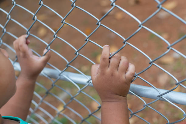 istock Asia children hand holding on mesh fence 1076114420