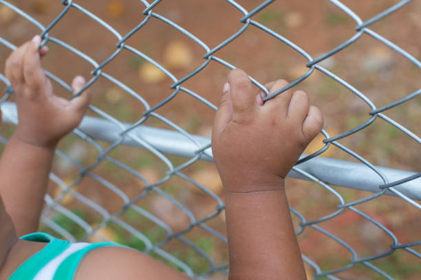 istock Asia children hand holding on mesh fence 1076114436