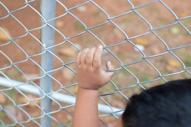 istock Asia children hand holding on mesh fence 1076114458