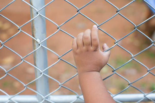 istock Asia children hand holding on mesh fence 1076114466