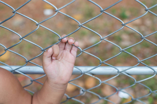 istock Asia children hand holding on mesh fence 1076114486