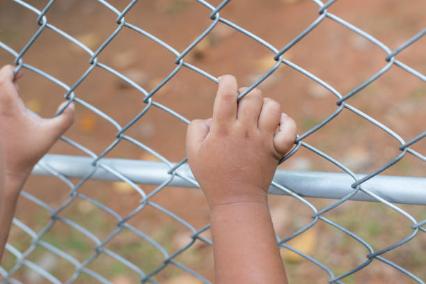 istock Asia children hand holding on mesh fence 1076114504