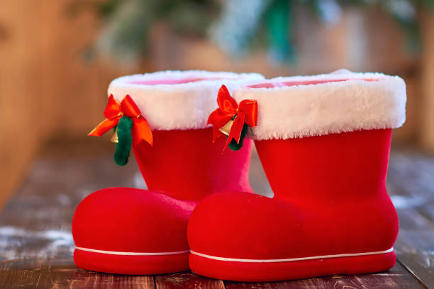 istock Red Christmas boot with white border and small bells on wooden table 1076119722
