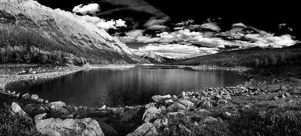 Panoramic black and white shot of Medicine Lake in the beautiful wilderness landscape of the Canadian Rockies in Jasper National Park, Alberta, Canada. Multiple files stitched.