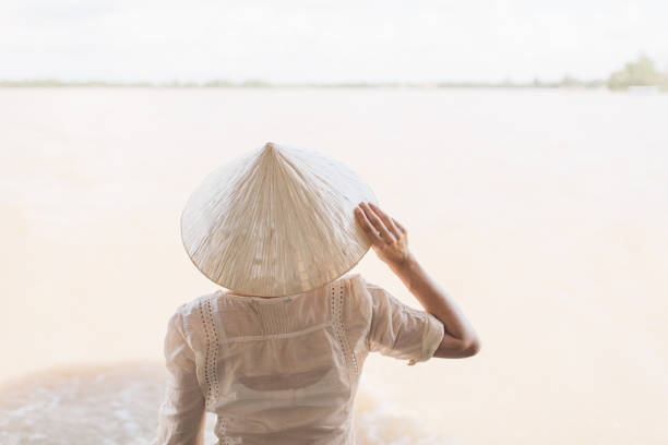 istock Rear View Of Woman Wearing Asian Style Conical Hat By Lake 1076158708