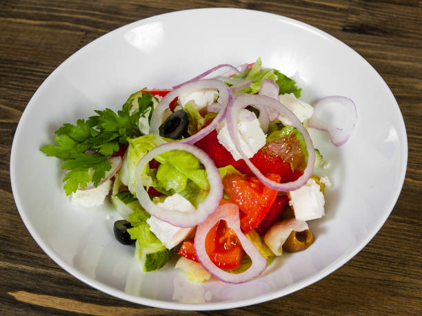 istock vegetable salad with cheese, cabbage, pepper, tomato and cucumber on wooden table. 1076162712