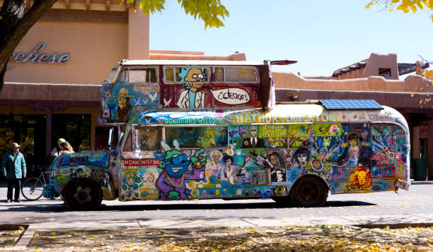 Santa Fe, NM: A vintage hippie bus parked on the Santa Fe Plaza, with typical adobe architecture in the background.
