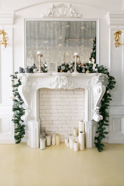 istock White fireplace decorated with candles and fir branches. Decorated Christmas tree. Classic apartments, morning in hotel 1076186702