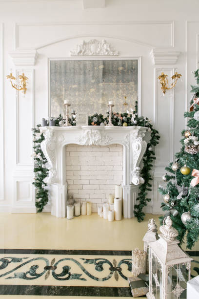 istock White fireplace decorated with candles and fir branches. Decorated Christmas tree. Classic apartments, morning in hotel 1076186856