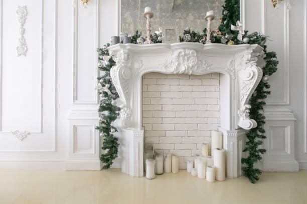 istock White fireplace decorated with candles and fir branches. Decorated Christmas tree. Classic apartments, morning in hotel 1076186882