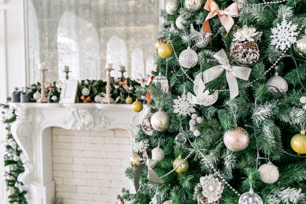 istock White fireplace decorated with candles and fir branches. Decorated Christmas tree. Classic apartments, morning in hotel 1076187602