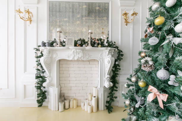 istock White fireplace decorated with candles and fir branches. Decorated Christmas tree. Classic apartments, morning in hotel 1076187648