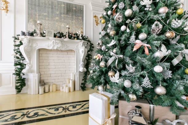 istock White fireplace decorated with candles and fir branches. Decorated Christmas tree. Classic apartments, morning in hotel 1076187990