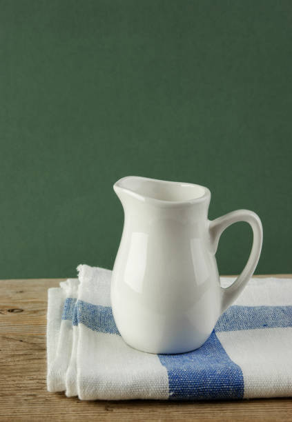 istock White jug and dishcloth on old wooden table over green background 1076200244
