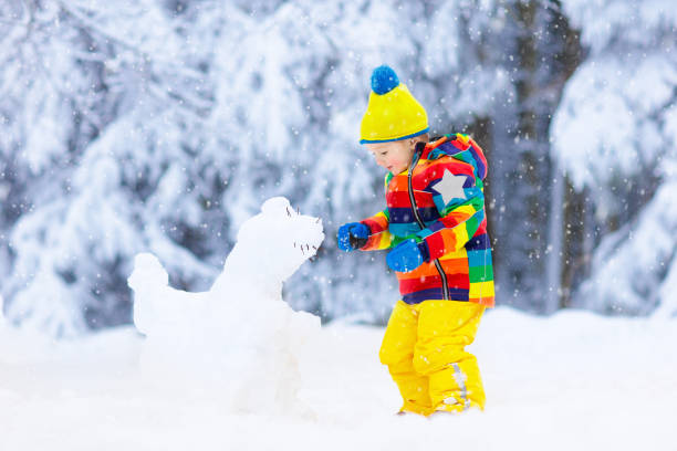istock Child making snowman. Kids play in snow in winter 1076202130
