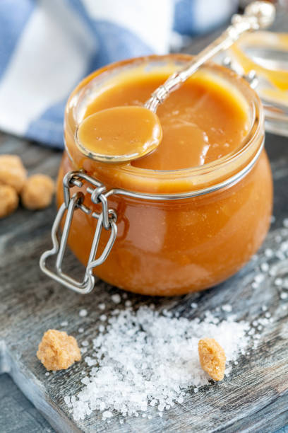 istock Spoon in a glass jar with salted caramel close-up. 1076202282