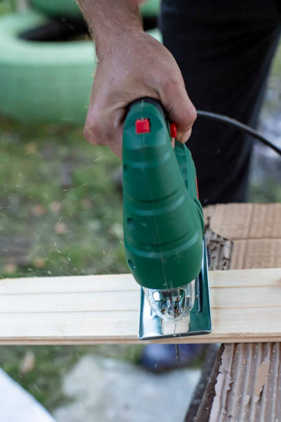 istock Man cuts wood products, using electric jigsaws outdoors 1076203830