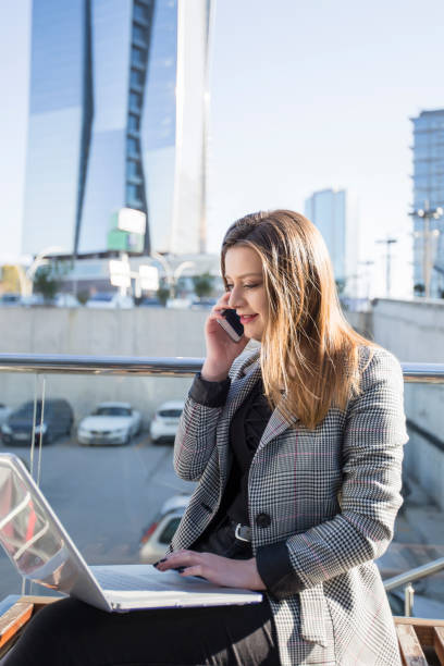 istock Beautiful woman talking on cell phone and working with laptop 1076205506