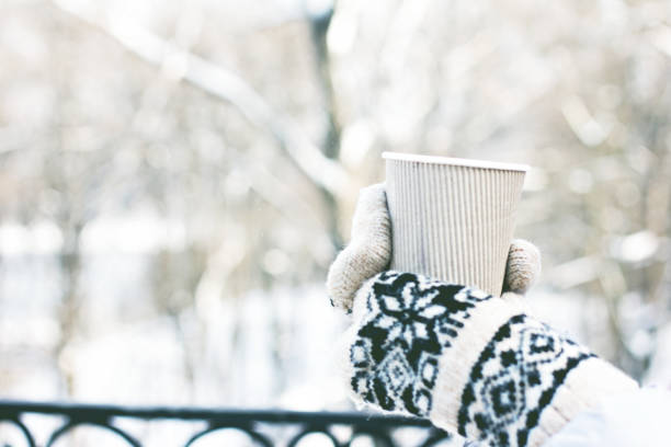 istock Female hands in white and black mittens holding steaming  cup 1076209714