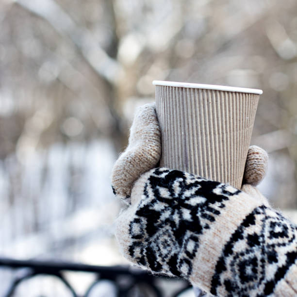 istock Female hands in white and black mittens holding steaming  cup 1076209888