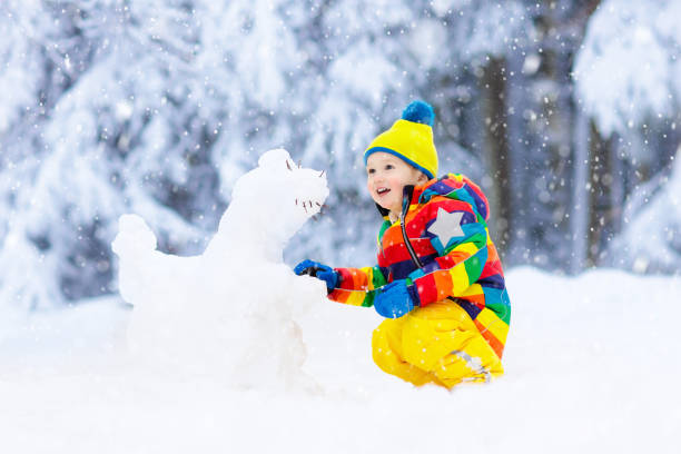 istock Child making snowman. Kids play in snow in winter 1076210068