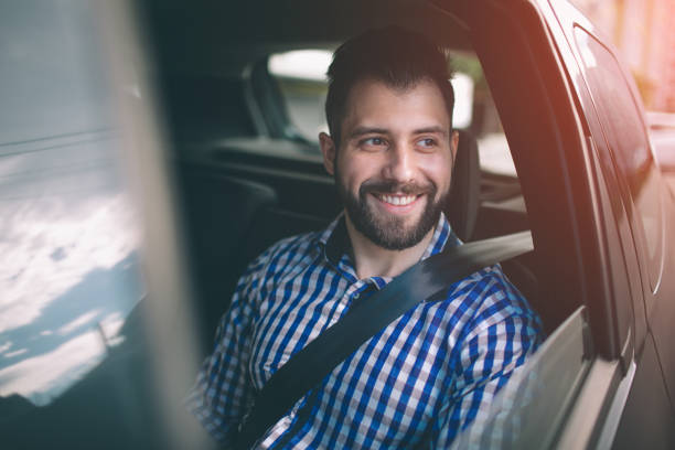 istock Beautiful man smiling while sitting on back seat in the car 1076211824