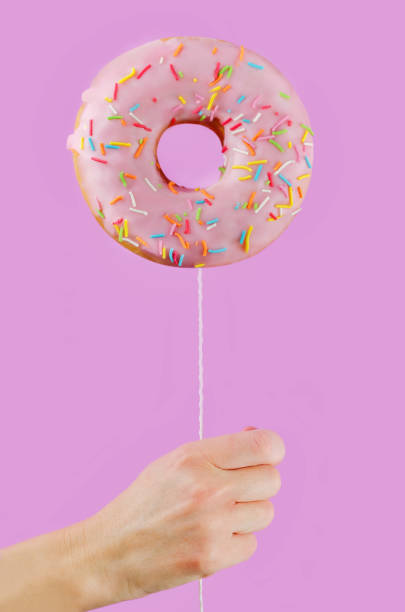 istock Donut in hand on a pink background 1076211998