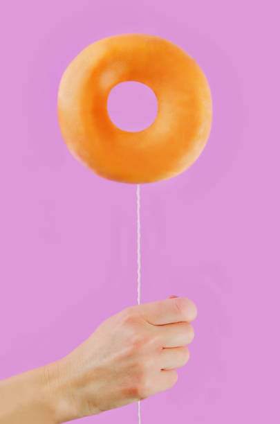 istock Donut in hand on a pink background 1076212046