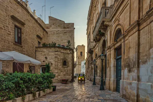 Stone buildings on a cobblestone street in the old town area of Polignano a Mare in the Puglia region of Italy during early morning in the summer