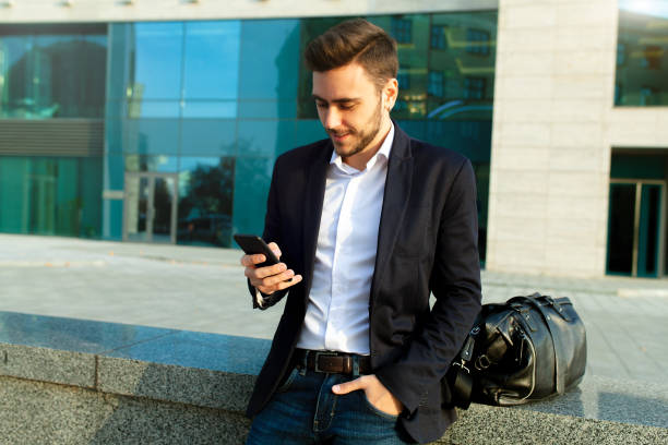 istock Young urban professional man using smart phone. Businessman holding mobile smartphone using app texting sms message wearing jacket 1076229964