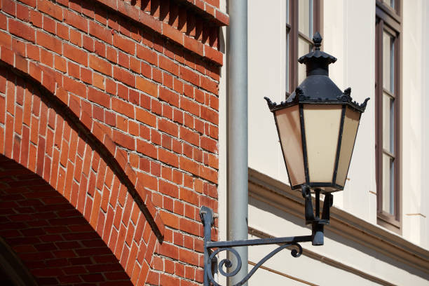 An antique designed street lighting lamp on clay brick wall of the vintage style farmhouse or barn building. Exterior decoration object equipment, close-up and selective focus.