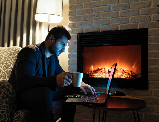 istock Man chatting online and drinking coffee next to fireplace 1076234944