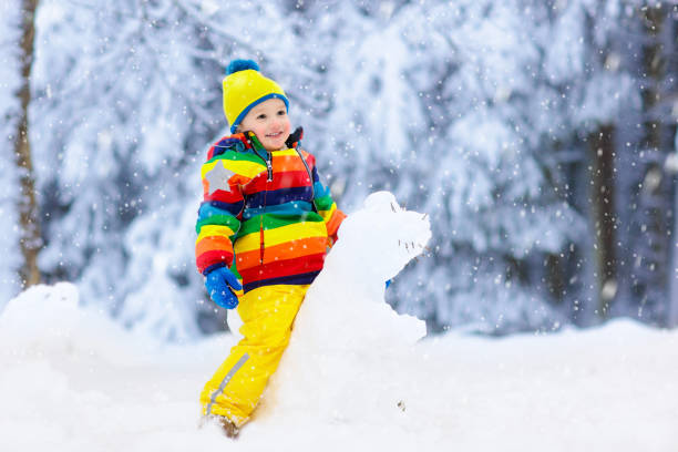 istock Child making snowman. Kids play in snow in winter 1076236290