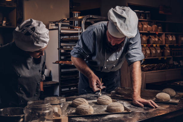 istock Cooking master class in bakery. Chef with his assistant showing ready samples of baking test in kitchen. 1076240130