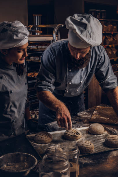 istock Cooking master class in bakery. Chef with his assistant showing ready samples of baking test in kitchen. 1076241902