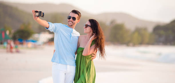 istock Happy couple taking a selfie photo on white beach. 1076242640