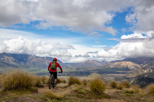 A mountain biker rides along the ridge and descends the mountain with beautiful scenery way down below