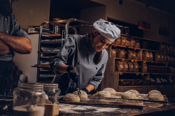 кулинарный мастер-класс по пекарне. шеф-повар со своим помощником показывает готовые образцы теста выпечки на кухне. - hat women chef occupation стоковые фото и изображения