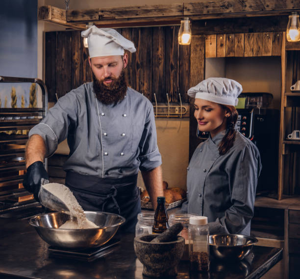 istock Chef pours the flour into a bowl. Chef teaching his assistant to bake the bread in the bakery. 1076246076